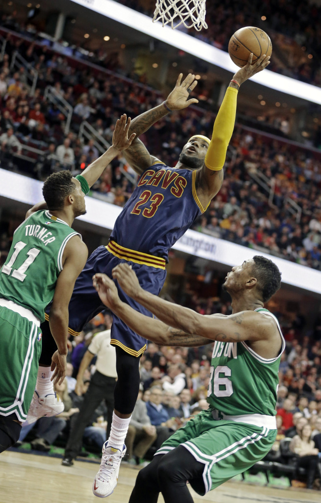 The Cleveland Cavaliers’ LeBron James shoots against the Celtics’ Evan Turner (11) and Marcus Smart in the first quarter of Tuesday night’s game in Cleveland. James scored 27 points in just 26 minutes on the court.