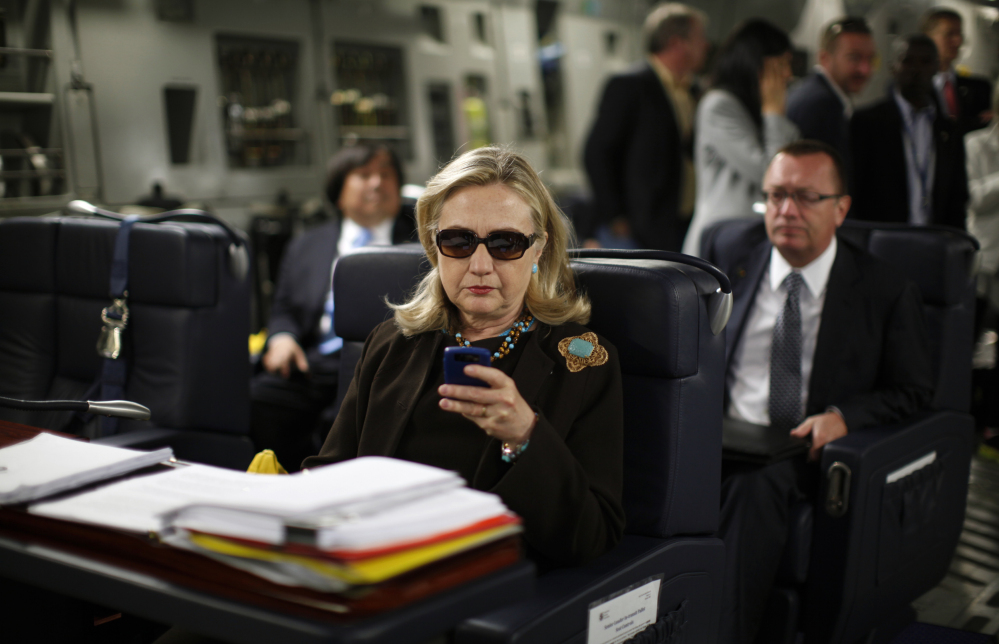 In this 2011 file photo, then-Secretary of State Hillary Clinton checks her Blackberry from a desk inside a C-17 military plane.