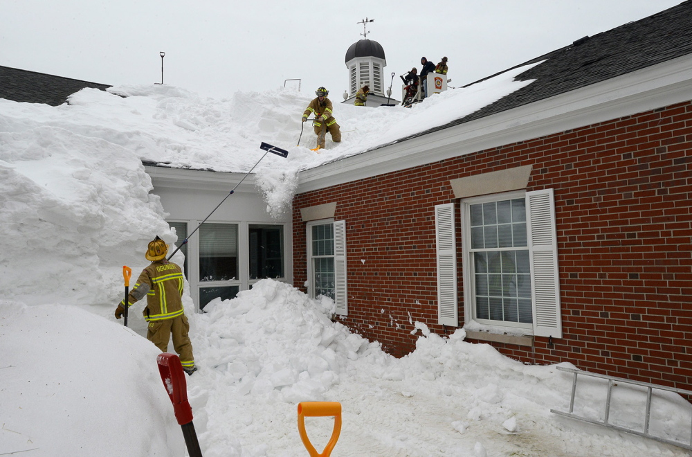 Firefighters from Ogunquit and Wells shovel snow off the Wells Public Library on Thursday after the roof bowed under the weight.