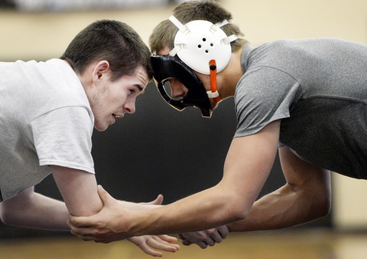 Dominick Day, right, training this week with a Biddeford teammate, Brian Livermore, now wrestles with a mask after breaking his nose during a match. Day, the Class A champion at 152 pounds, will seek a New England title after finishing sixth a year ago.