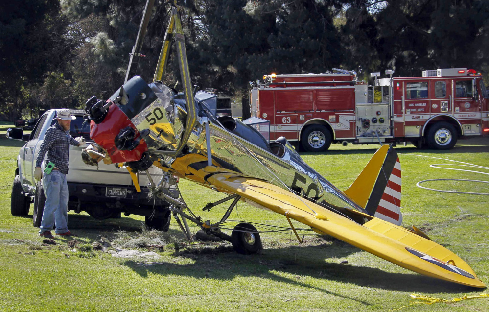 Associated Press
The World War II-era trainer airplane that actor Harrison Ford crash-landed Thursday is removed from Penmar Golf Course in the Venice area of Los Angeles on Friday. Ford, 72, is hospitalized with undisclosed injuries that his publicist says are not life-threatening. The actor was flying the plane when it lost engine power shortly after takeoff from nearby Santa Monica, Calif., Municipal Airport.