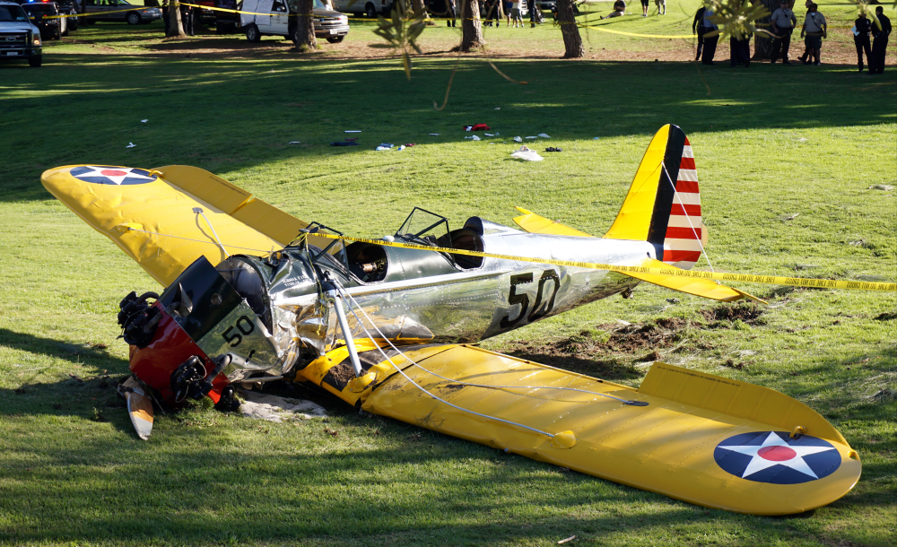 A small vintage airplane rests on the ground after actor Harrison Ford, below right, crash-landed on the Penmar Golf Course in the Venice area of Los Angeles on Thursday. The Associated Press