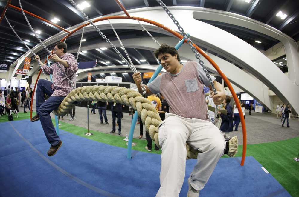 Phillip Chu Joy, left, and Juan Pablo Cabrejos Meza, right, ride a swing in the Biba smart playground at the Game Developers Conference, Wednesday, in San Francisco. The Associated Press