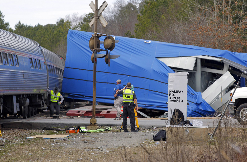 Police and others work the scene of a truck-train collision Monday in Halifax, N.C. The 16-foot-square electrical building that the truck was hauling was wrapped in blue plastic.