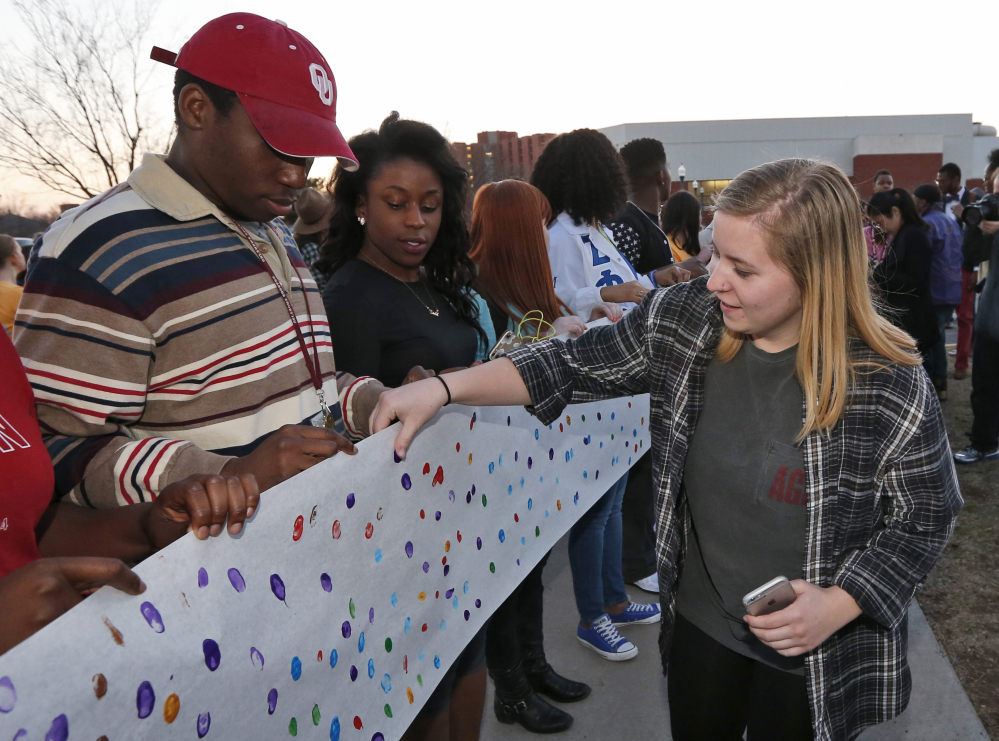 University of Oklahoma junior Brooke Aston, right, of Rockwall, Texas, adds her fingerprint to a sign to be carried to the now-closed University of Oklahoma’s Sigma Alpha Epsilon fraternity house during a rally in Norman, Okla., on Tuesday.
