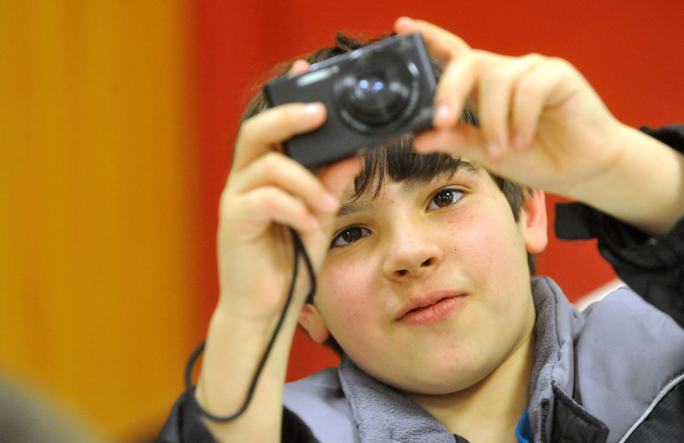 Owen Schuchardt, 11, snaps a photo during a photo club class with photographer Eric Gottesman at the Alfond Youth Center on Wednesday.
