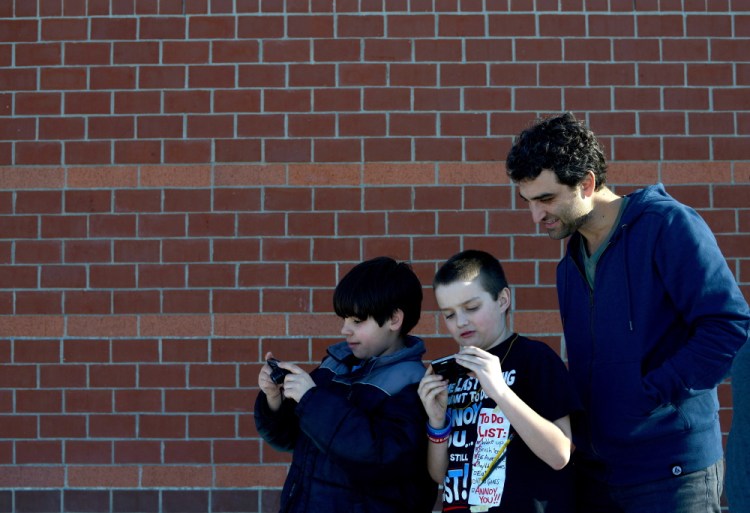 Owen Schuchardt, left, and Jacob Luff, center, share their photos with their photography teacher, Eric Gottesman, during a photo club class at the Alfond Youth Center on Wednesday.