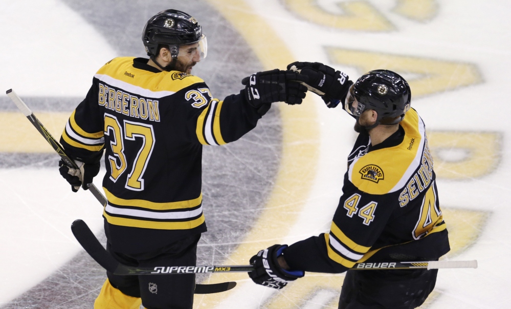 Bruins center Patrice Bergeron (37) is congratulated by teammate Dennis Seidenberg after his goal against the Tampa Bay Lightning during the third period of Thursday night’s game in Boston. The Bruins won, 3-2, in an overtime shootout.
