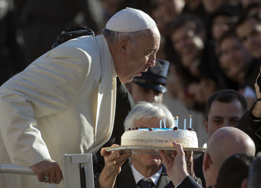 Pope Francis blows out candles on a birthday cake on the occasion of his 78th birthday as he arrives for his weekly general audience in St. Peter’s Square at the Vatican. The Pontiff marks his second anniversary riding a wave of popularity that has reinvigorated the Catholic Church in ways not seen since the days of St. John Paul II.  The Associated Press