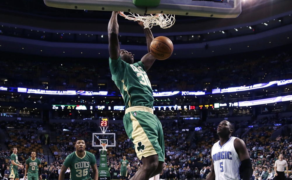 Celtics forward Brandon Bass slams a dunk as Orlando Magic guard Victor Oladipo looks on during the first quarter of Friday night’s win by the Celtics in Boston.