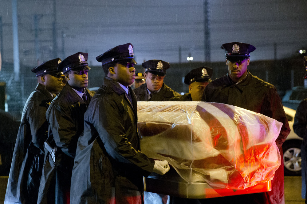 The remains of Philadelphia Police Officer Robert Wilson III are transferred to a horse-drawn hearse during a winter rainstorm on Saturday in Philadelphia. Wilson was shot and killed March 5 after he and his partner exchanged gunfire with two suspects trying to rob a video game store.