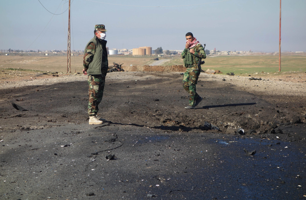 In this undated photo made avaialble Saturday by the Kurdistan Region Security Council (KRSC), Kurdish soldiers survey the site of a bomb attack on a road between Mosul, Iraq, and the Syrian border in northern Iraq.