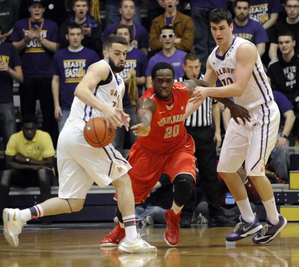 Albany’s Peter Hooley, left, deflects the ball away from Stony Brook’s Jameel Warney Jr. in the first half of Saturday’s America East title game. Albany won on Hooley’s 3-pointer in the final seconds.