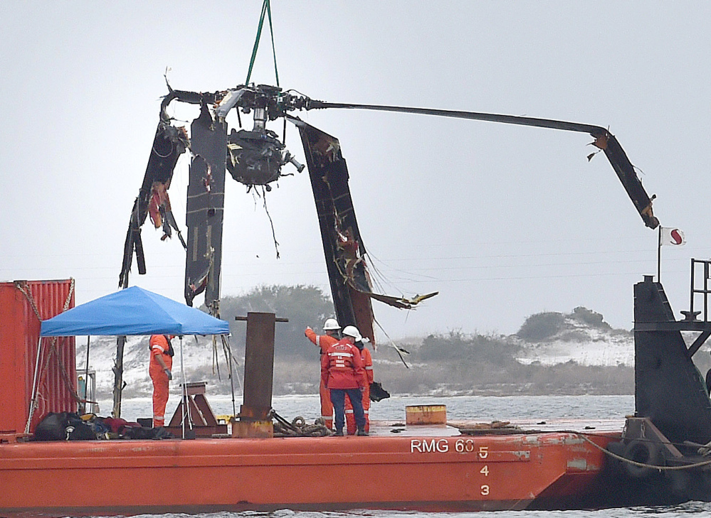 Crews lower a piece of a Black Hawk helicopter onto a barge Friday in Navarre, Fla. The helicopter carrying 11 servicemen crashed in dense fog during a training mission Tuesday.