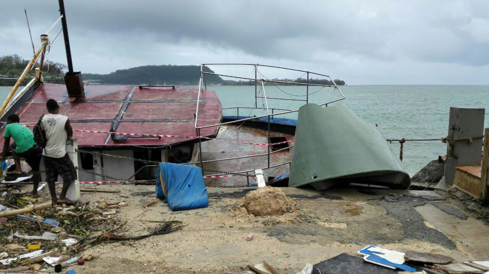 Locals stand by a tilted boat in Port Vila, Vanuatu, on Sunday after Cyclone Pam ripped through the tiny South Pacific archipelago.