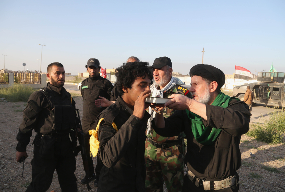 A young volunteer kisses the Quran, the Muslim holy book, as a Shiite cleric blesses him before going into battle against Islamic State fighters in Tikrit, 130 kilometers (80 miles) north of Baghdad, Iraq, Sunday.