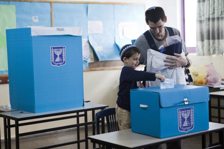 An Israeli settler votes, with the help of a child, in the settlement of Efrat, West Bank, Tuesday.