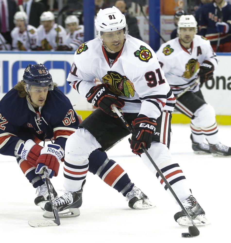 Brad Richards of the Blackhawks controls the puck while being hounded by New York’s Carl Hagelin on Wednesday night in New York. Richards scored in Chicago’s 1-0 win.