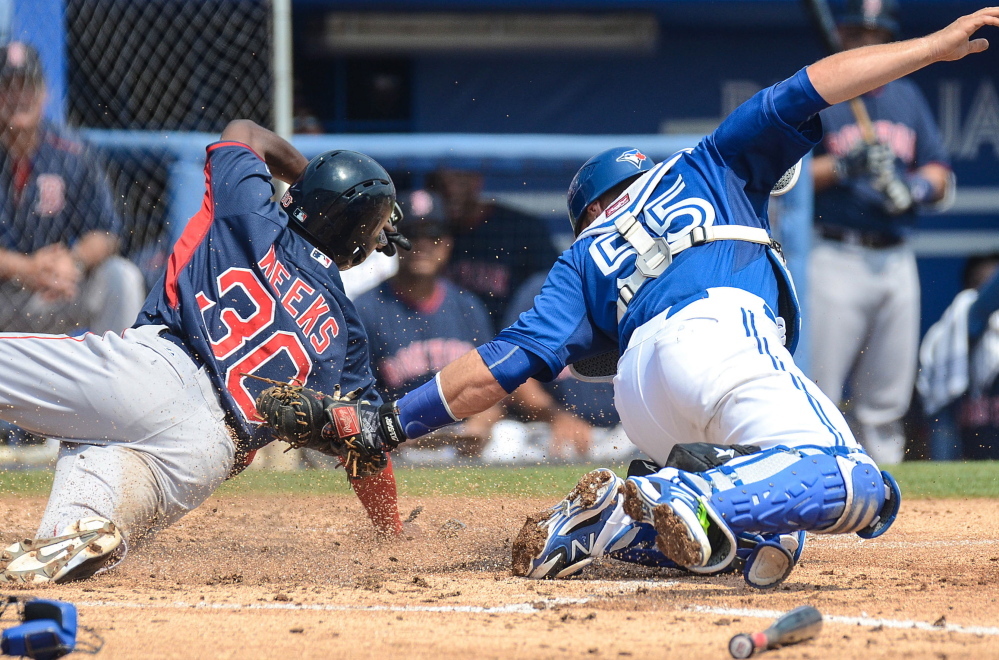 Boston second baseman Jemile Weeks slides in safely past the tag of Toronto catcher Russell Martin in the third inning of a 6-3 spring training loss by the Red Sox at Dunedin, Fla., on Thursday.