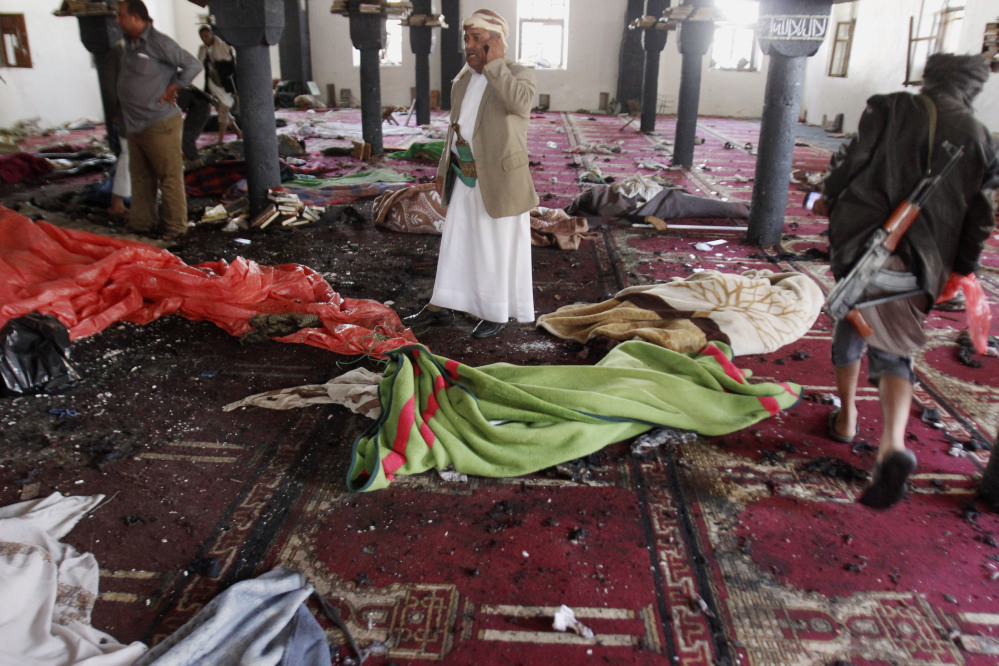 People stand amid bodies covered with blankets in a mosque after a suicide attack during the noon prayer in Sanaa, Yemen, on Friday.