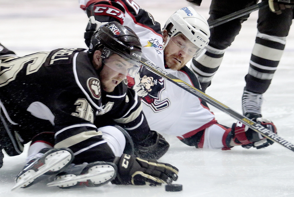 Garrett Mitchell of the Hershey Bears tries to keep the puck away from an incoming Alexandre Bolduc of the Portland Pirates during the first period of Hershey’s 3-2 overtime victory at Cross Insurance Arena on Friday night.