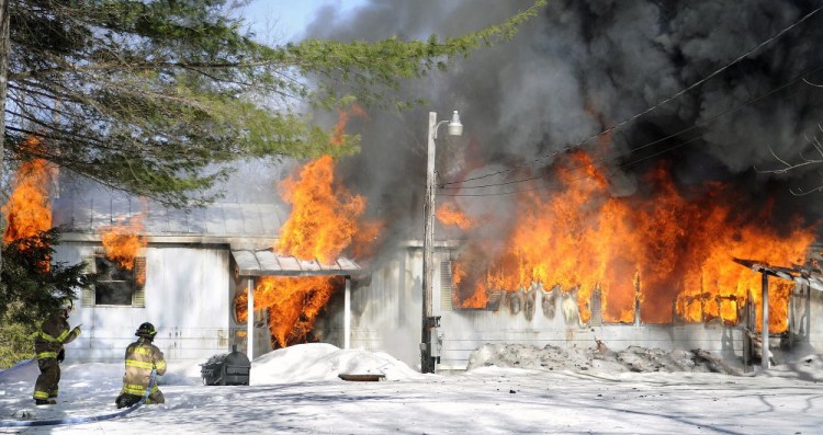 Firefighters work to put out a fire at a mobile home in Readfield on Monday morning.