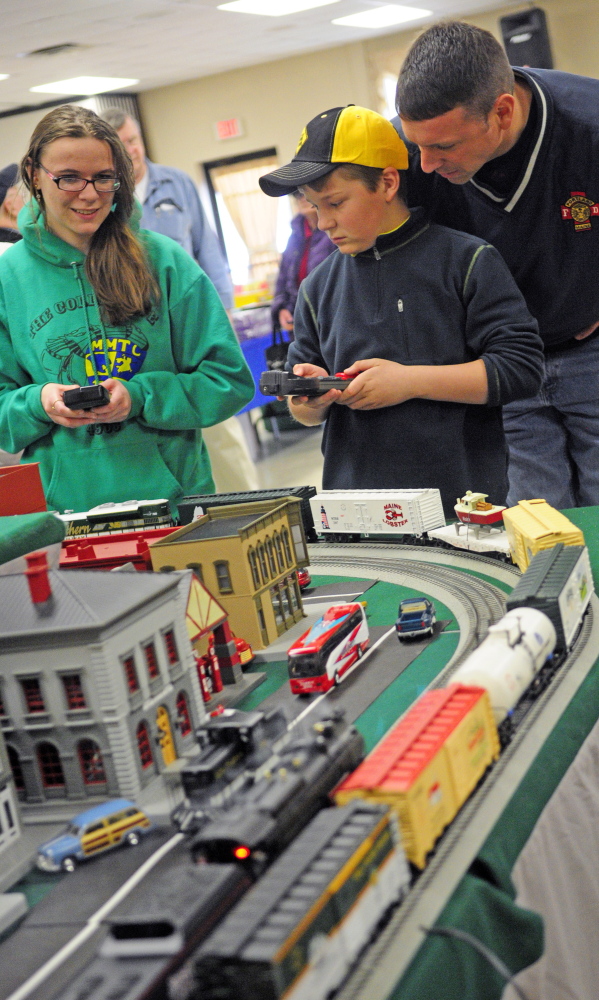 Oakland’s Mary Wunderlich, left, and Jackson Small of Cumberland use remotes to control trains during the Maine3Railers Model Railroad Club’s show on Saturday. Small’s father, Dan Small, watches at right.