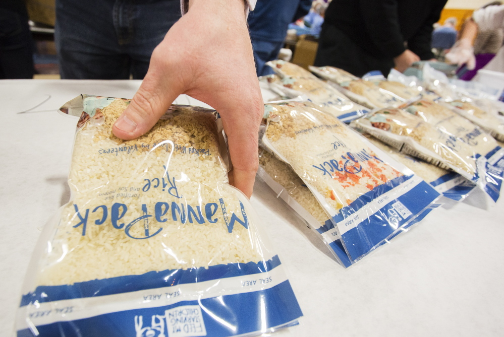 A volunteer finishes meal packs, assembled for starving children around the world, at Deering High School in Portland on Sunday.