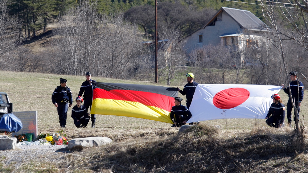 The German, left, and Japanese flags are displayed during a ceremony with family members of Japanese victims in the area where the Germanwings jetliner crashed in the French Alps, in Le Vernet, France, on Sunday.