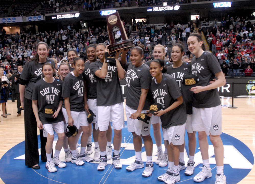 Connecticut players pose with the trophy after their 91-70 win over Dayton in a regional final Monday in Albany, N.Y.