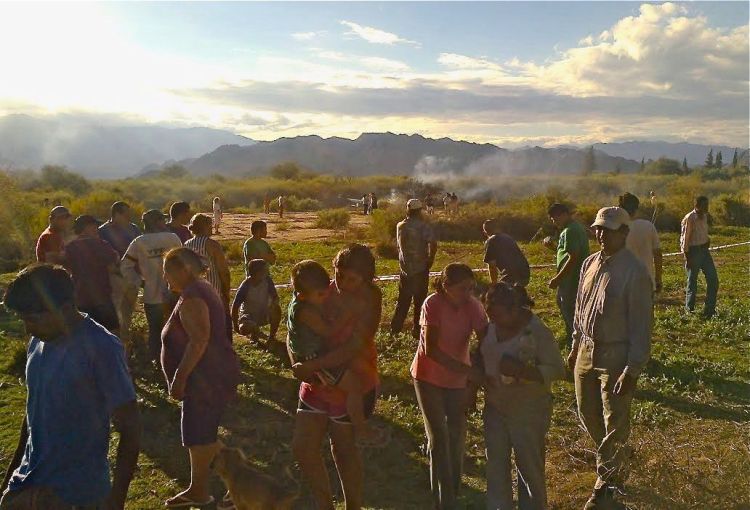 People gather near the smoking remains of a helicopter that crashed with another near Villa Castelli in the La Rioja province of Argentina, on Monday. Two helicopters carrying passengers filming the popular European reality show "Dropped" crashed  in the remote area of northwest Argentina, killing everyone on board, authorities said. The Associated Press