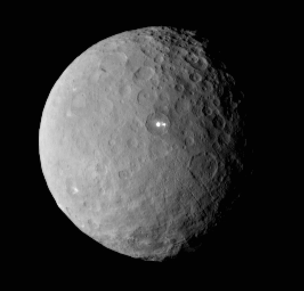 As Dawn approached Ceres, it spotted a pair of puzzling bright spots inside a crater. Scientists think the shiny dots may be exposed ice or salt. This image was captured from a distance of nearly 29,000 miles. The dots are above and right of center. The Associated Press / NASA