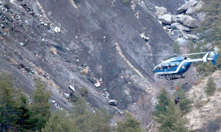 A rope hangs from a rescue helicopter flying past debris from the Germanwings passenger jet, scattered on the mountainside, near Seyne les Alpes, French Alps on Tuesday. The Associated Press