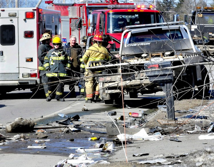 The driver of a truck involved in a fatal accident in Madison, at center, between vehicles, speaks with firefighters Tuesday as police reconstruct the scene of the accident on U.S. Route 201 in Madison. 