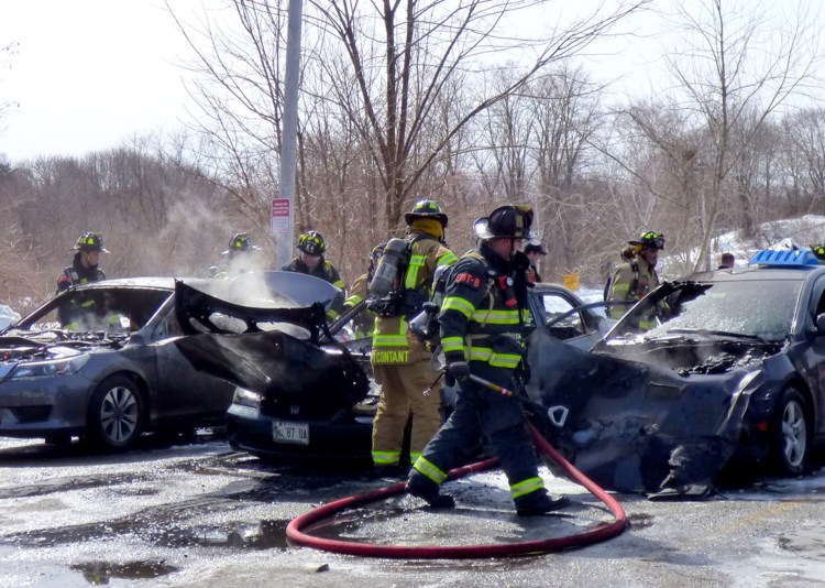 Firefighters finish extinguishing burning cars Tuesday in a Westbrook parking lot. The fire appeared accidental.