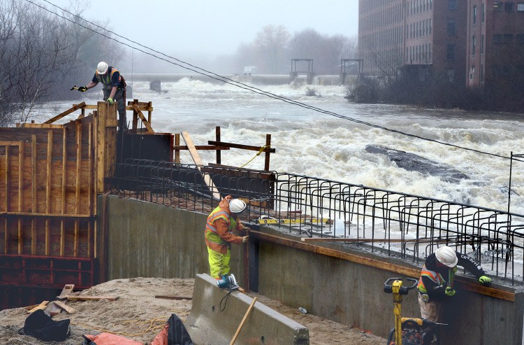 A construction crew work on a bridge alongside a raging Saccarappa Falls on the Presumpscot river in Westbrook after heavy rains. John Patriquin/Staff Photographer