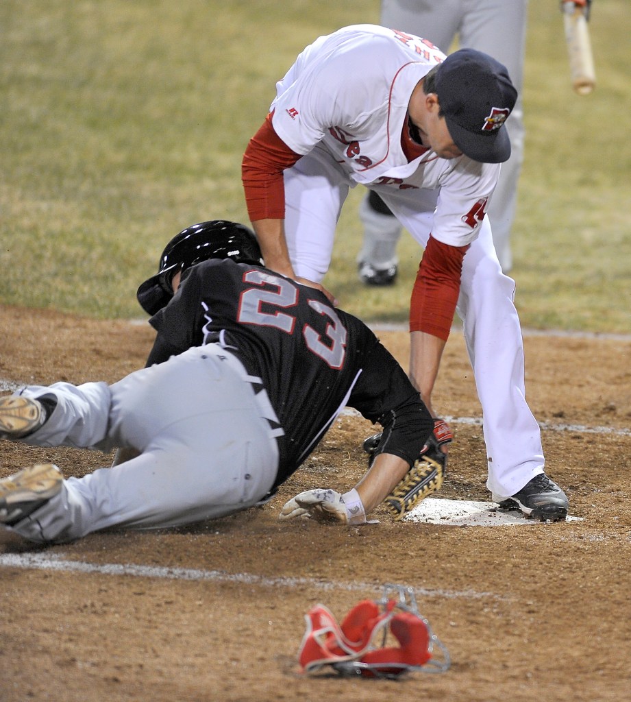 Sea Dogs relief pitcher Pat Light puts the tag on New Britain runner Jonathan Aro at home plate to save a run after a passed ball in an April game.