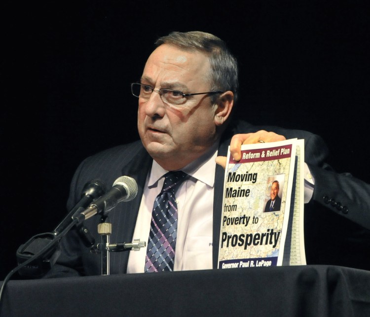 Gov. Paul LePage holds up a copy of his tax reform plan during Thursday night's town hall meeting in Saco. LePage continues to fight for his proposals, but he also has appeared resigned at times to seeing lawmakers reject key portions of his plan.