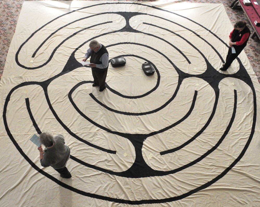 Suzan Katzir, left, the Rev. Jim Gill and Jenifer Lewis walk the labyrinth Friday in the Winthrop Center Friends Meeting House, where the St. Andrew’s Episcopal Church meets.