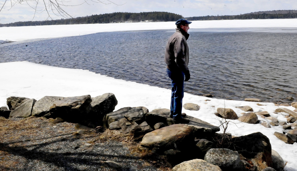 Tim Comeford checks the amount of ice on Long Pond in Belgrade on Sunday. Comeford said the lake’s ice usually is all gone by the third week of April.
