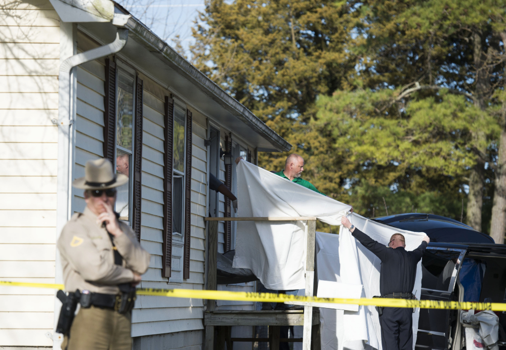 Sheets are held as a body is removed from the home where police say seven children and one adult were found dead Monday in Princess Anne, Md. Officers were sent to the home after being contacted by a concerned co-worker of the adult.