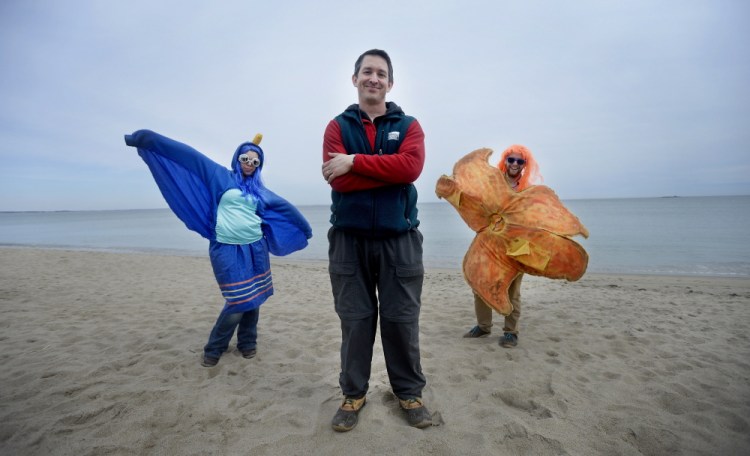Drew Dumsch, center, executive director of The Ecology School, along with staff members Haley Diamond, left, dressed as a great blue heron, and Aaron Altabet, dressed as a sea star, at the beach near the school in Saco.