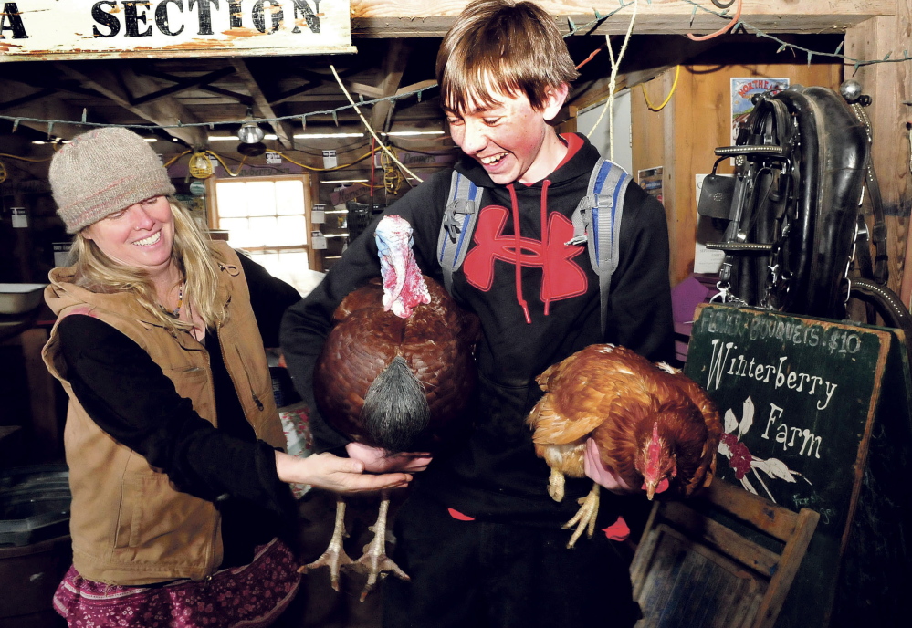 Farm owner Mary Perry hands a turkey to student Tyler Sterry during a field trip to Winterberry Farm.