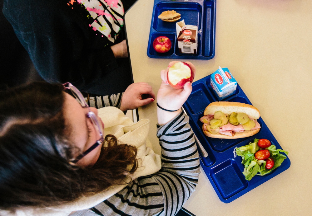Seventh-grader Hailey Remington bites into an apple. Cafeterias across Maine are shifting away from institutional food, with whole wheat, dark green vegetables and fruit on school menus more often. Whitney Hayward / Staff Photographer