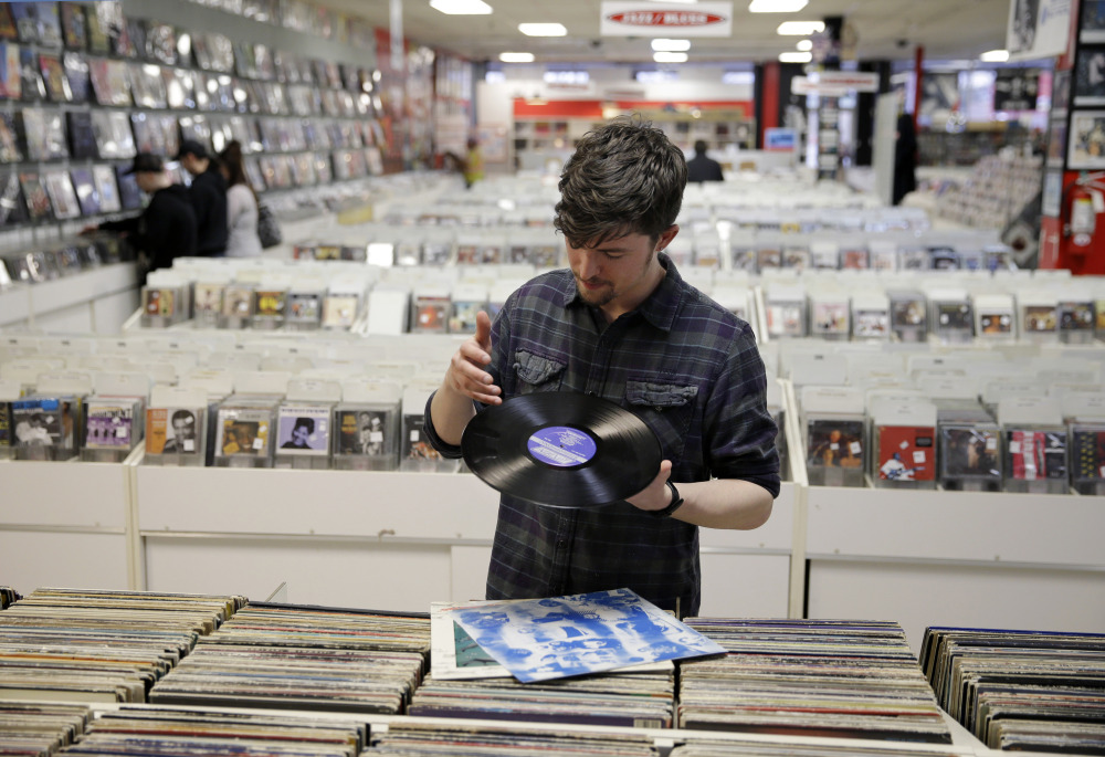 Record clerk Josh Kelly wipes a dust speck from a used LP record as he put it in a sales bin at Vintage Vinyl Records this month in Fords, N.J. A recent Rutgers graduate, Kelly is working at the record store and living with friends while he tries to land a job in journalism or radio programming.
