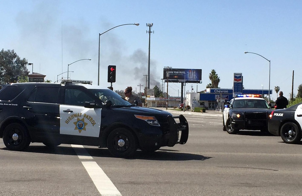 Highway patrol officers block off Herndon Avenue at Highway 99 after a natural gas explosion in Fresno, Calif., on Friday. Smoke from the fire can be seen in the background.