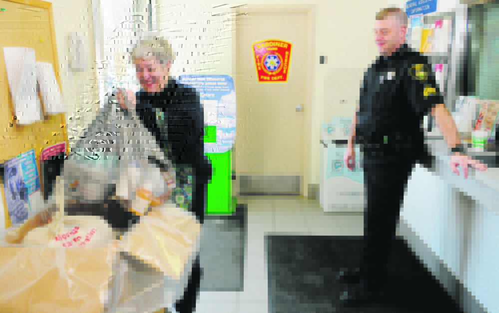 Carmen McCurdy, left, chats with Gardiner Police Sgt. Todd Pillsbury as she drops of medicine during the annual drug take-back at the Gardiner police station in 2013. Sheriff departments across Maine are taking over the event as the DEA says it can’t fund the event.