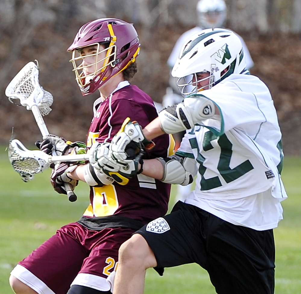 Finn Raymond, left, of Cape Elizabeth is held back by Cooper Chap of Waynflete while looking to pass Friday during their season-opening boys’ lacrosse game in Portland. The Capers won, 18-6.