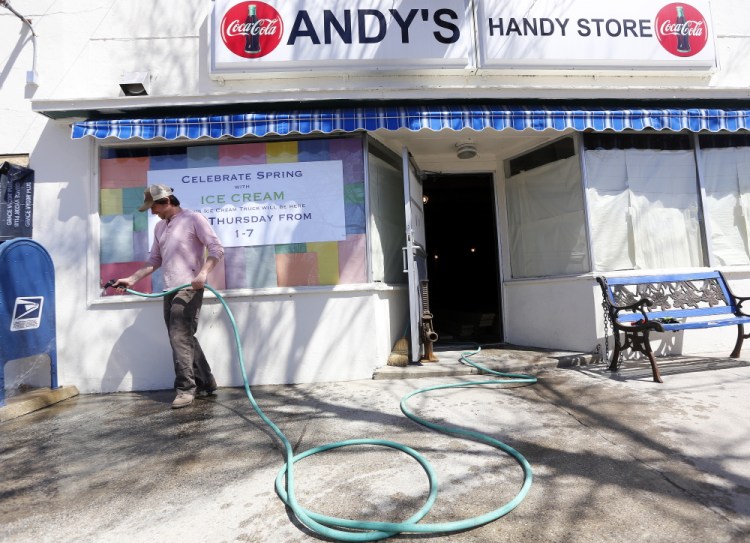 Sean Ireland, one of the new owners of the former Andy’s Handy Store in Yarmouth, cleans the sidewalk in front of the building where Otto Pizza will locate along with two other businesses. The store’s interior has been gutted for rehabilitation.