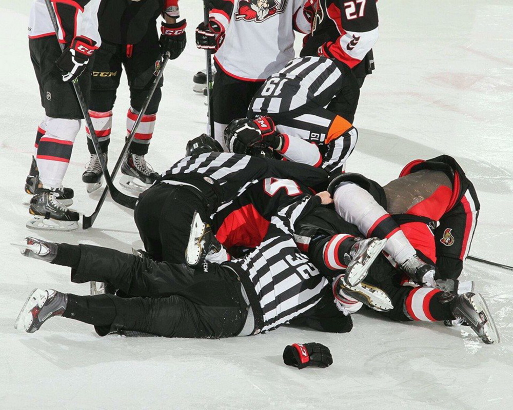 Linesman Joe Andrews, No. 32, is buried in a scrum during a Portland Pirates game. Andrews is known for having a rapport with players and coaches.
